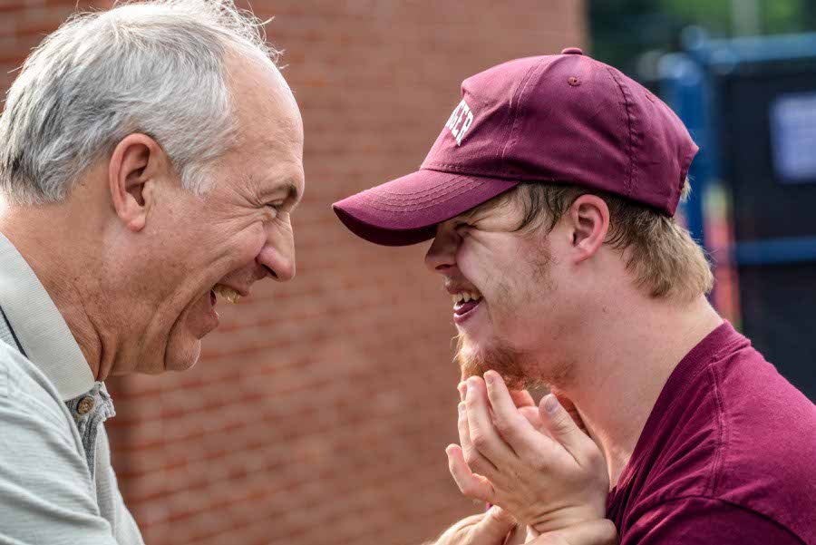 Two men laughing, one with a disability